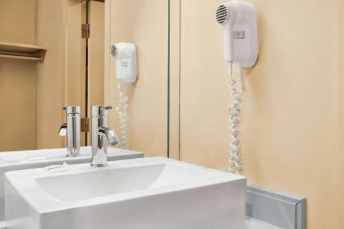 ein Badezimmer mit einem Waschbecken und einem Telefon an der Wand in der Unterkunft Hotel Days Inn Blainville & Centre de Conférence in Blainville