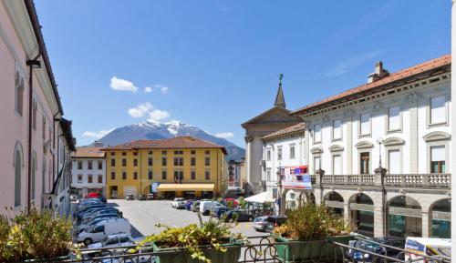 een stadsstraat met gebouwen en een berg op de achtergrond bij Albergo Roma in Tolmezzo