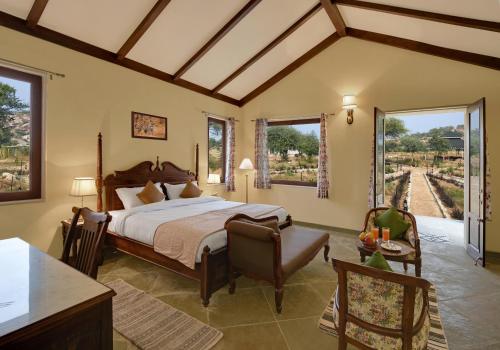 1 dormitorio con 1 cama, mesa y sillas en Jawai Leopard Safari Lodge, en Bera