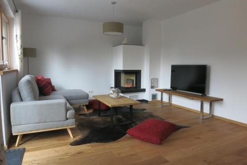 a living room with a couch and a tv at Seebach Chalets in Scheffau am Wilden Kaiser