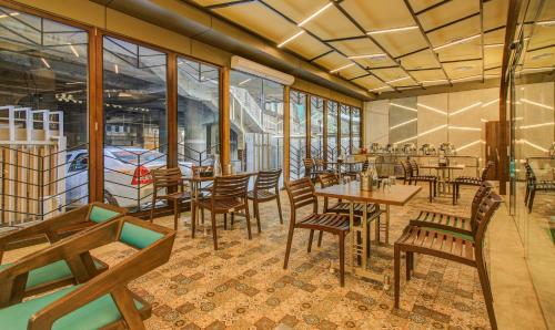 a restaurant with wooden tables and chairs and windows at Hotel Metropole Inn in Mumbai