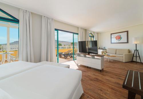 a hotel room with a large bed and a television at H10 Playa Esmeralda - Adults Only in Costa Calma
