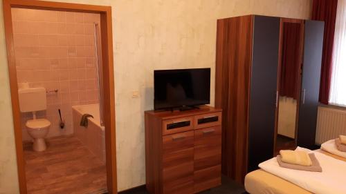 a bathroom with a television on a dresser with a toilet at Hotel & Pension Plagwitzer Hof in Leipzig