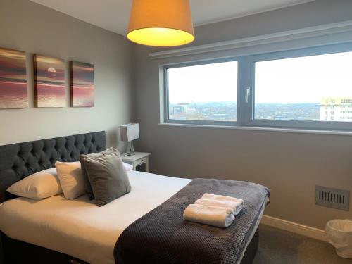 Schlafzimmer mit einem Bett und einem großen Fenster in der Unterkunft High View Serviced Apartment in Cardiff