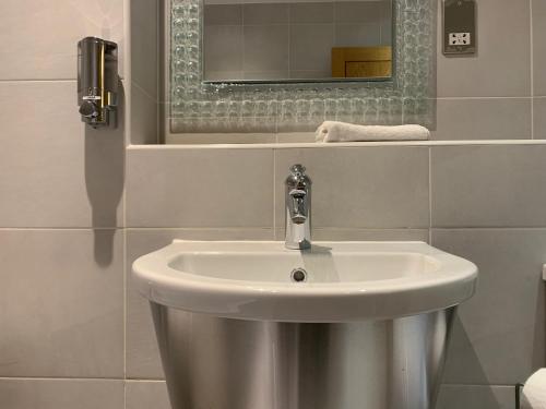 ein weißes Waschbecken im Bad mit Spiegel in der Unterkunft High View Serviced Apartment in Cardiff