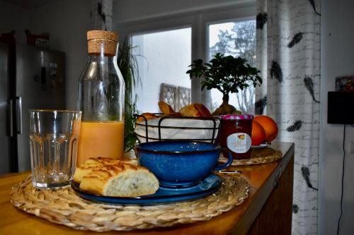 - une table avec une assiette de pain et une bouteille de jus d'orange dans l'établissement La Korrigane, à Groix