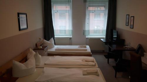 a hotel room with two beds and two windows at Hotel & Pension Plagwitzer Hof in Leipzig