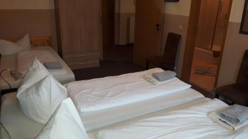 two beds in a hotel room with white sheets at Hotel & Pension Plagwitzer Hof in Leipzig