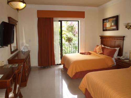 a hotel room with two beds and a television at Gran Real Yucatan in Mérida
