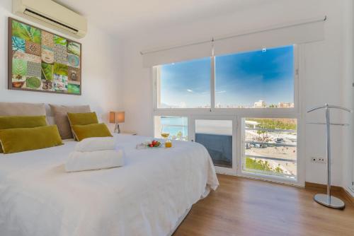 Schlafzimmer mit einem weißen Bett und Strandblick in der Unterkunft LU&CIA Málaga Skyline in Málaga