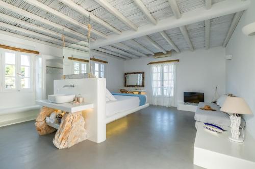 a white bedroom with a bed and a tv at Evlalia Studios & Villas in Skopelos Town