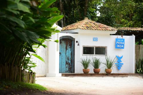 a small white building with a blue door and potted plants at Hotel Boutique Perainda in Trancoso