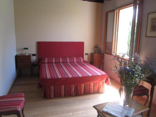 Un dormitorio con una cama roja y una mesa con flores en Fara1911 en Fonte