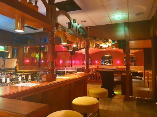 a bar in a restaurant with yellow stools at CAREA Residenz Hotel Harzhöhe in Hahnenklee-Bockswiese