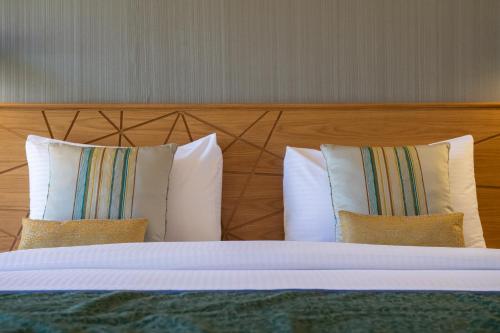 a bed with three pillows and a wooden headboard at استراحة الفيحاء AL Feyhaa Resthouse in Samail