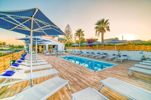 una piscina con sillas y sombrillas y una piscina en Emi Seaside en Amoudara Herakliou