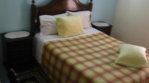 a bedroom with a bed with a checkered blanket and pillows at Residencial Porto Novo - Alojamento Local in Porto