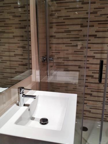 a bathroom with a white sink and a shower at Apto. Vista Playa Poniente in Gijón
