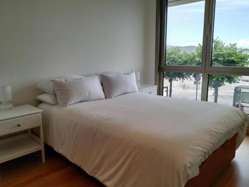 una camera da letto con un letto bianco con una finestra di Apto. Vista Playa Poniente a Gijón