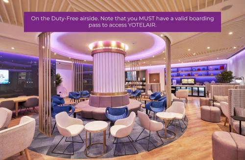 un vestíbulo con una zona de espera con sillas y mesas en YOTELAIR Istanbul Airport, Duty free - International Transit area, en Estambul