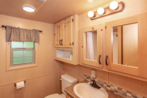 a bathroom with a toilet and a sink and a window at Sun Outdoors Lake Rudolph in Santa Claus