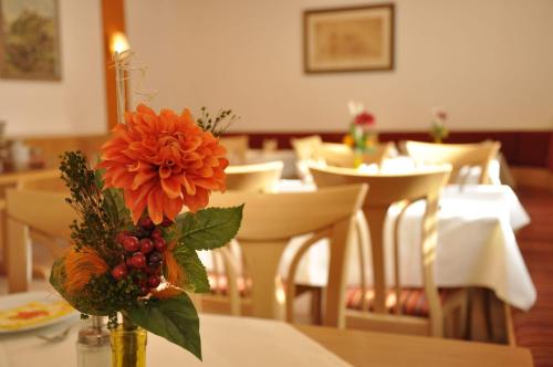a vase with a orange flower on a table at Hotel Gasthof zum Goldenen Lamm in Harburg