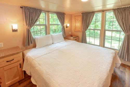 a bedroom with a large white bed with windows at Sun Outdoors Lake Rudolph in Santa Claus