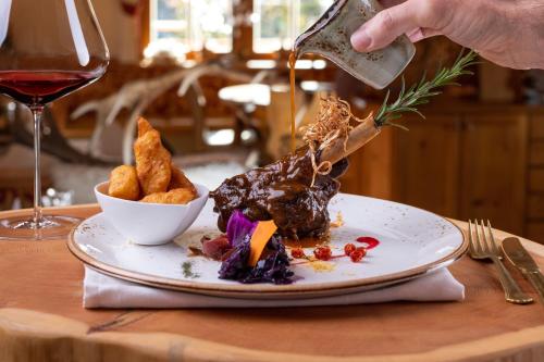 a person is pouring wine into a plate of food at Hotel und Alpen Apartments mit Sauna - Bürglhöh in Bischofshofen
