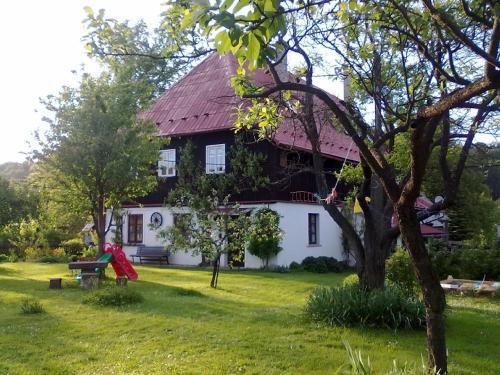 a woman sitting on a bench in front of a house at Pension Laura in Chřibská