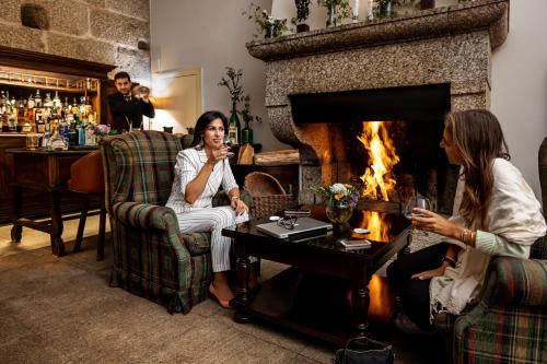 two women sitting in a living room with a fireplace at Pousada Mosteiro de Guimaraes in Guimarães