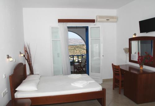 a room with a bed and a desk and a window at Aiolos Iraklia in Iraklia