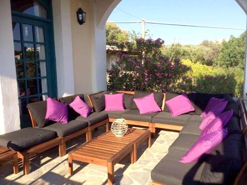 a couch with pink and purple pillows on a patio at 5 bedrooms villa at Limnos 250 m away from the beach with sea view enclosed garden and wifi in Lemnos