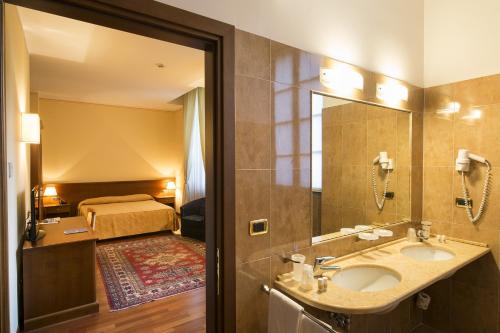 ein Bad mit einem Waschbecken und ein Bett in einem Zimmer in der Unterkunft Centro Paolo VI in Brescia