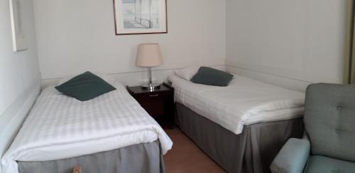 two beds in a room with a lamp and a chair at Kauppahotelli in Lahti