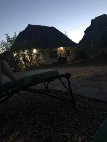 a person sitting on a bench in front of a house at BeB Sardegna2 Anjumasa village in Watamu