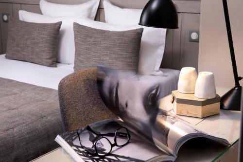 a table with a book and a lamp and a bed at Hôtel Hélios Opéra in Paris