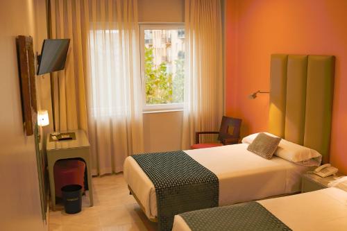 a hotel room with two beds and a window at Hotel Sancho in Madrid