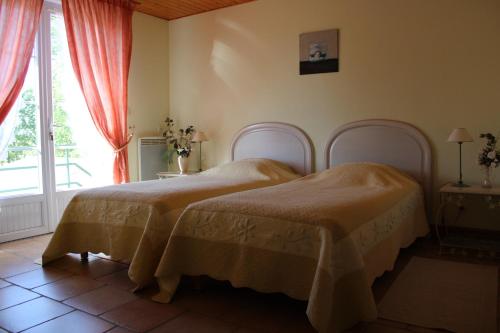 una camera da letto con due letti e una finestra di Le Logis du Château a Vieillevigne