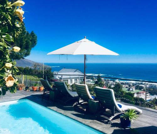 piscina con sedie e ombrellone e oceano di Boutique@10 a Città del Capo