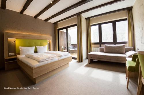 Hotel Sewenig في Müden: غرفة نوم بسرير وكرسي ونوافذ