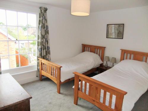 two twin beds in a room with a window at Admirals Cottage in Yarmouth
