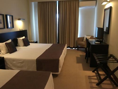 a hotel room with two beds and a desk and a television at Hotel SJ in Tondela