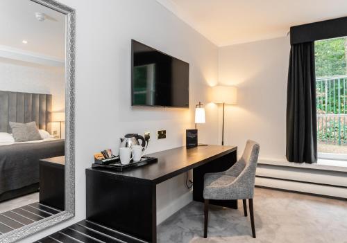 a hotel room with a desk and a mirror at Gorse Hill Hotel in Woking