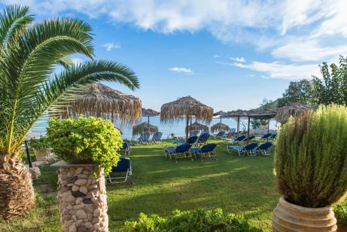 a lawn with chairs and umbrellas and the water at VillaPouliezos Apartments in Alikanas