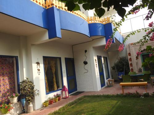 a house with a blue roof with plants and flowers at Coral Country Homestay in Agra