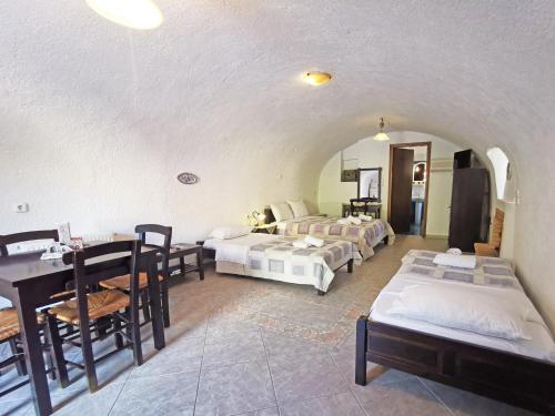 a room with three beds and a table and a dining room at Guesthouse Toxotis in Pirgos Dhirou