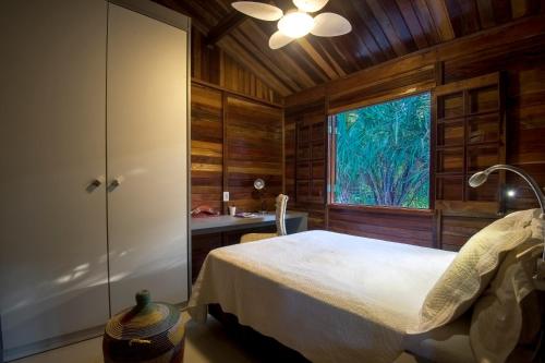 ein Schlafzimmer mit einem Bett in einem Zimmer mit einem Fenster in der Unterkunft Casinha de Madeira no Vale do Capão in Vale do Capao