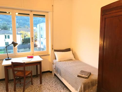 1 dormitorio con cama, escritorio y ventana en Appartamento Madeleine, en Levanto