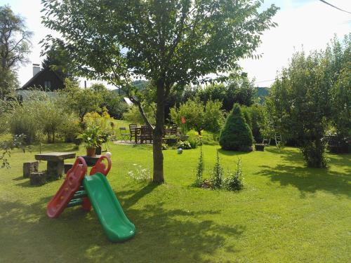 a playground with a slide and a tree in a yard at Pension Laura in Chřibská
