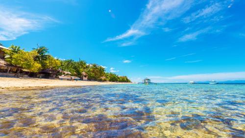 a beach with crystal clear water and a blue sky at Native House Resort powered by Cocotel in Moalboal
